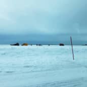 Jääauralla varustettu traktori, ambulanssi ja miehiä jäätiellä lumivallin takana.