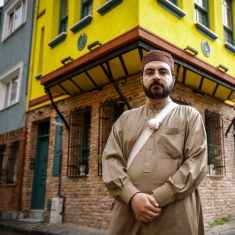 Muhammad Ali Mojaradi seisoo vanhan rakennuksen edessä kadulla.