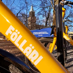 Kirkkaankeltainen kaupunkipyörä, jossa teksti Föllari, taustalla Turun tuomiokirkko.