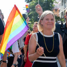 Magdalena Anderson håller i en regnbågsflagga på prideparad i Stockholm.