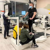 Premius kuntoutuksen fysioterapeutit Heidi Haromo ja Hanna Hellman auttavat Aarne Väänästä kävelyrobottiin Premiuksen tiloissa Kalevassa.