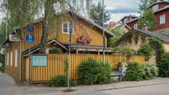 Keltainen puutalo kadunkulmassa, kyltti Rajaportin sauna, ympärillä puutaloja