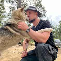 Husky-koira ja Tuomas heikkilä metsässä sylikkäin Inarissa kesällä 2024.