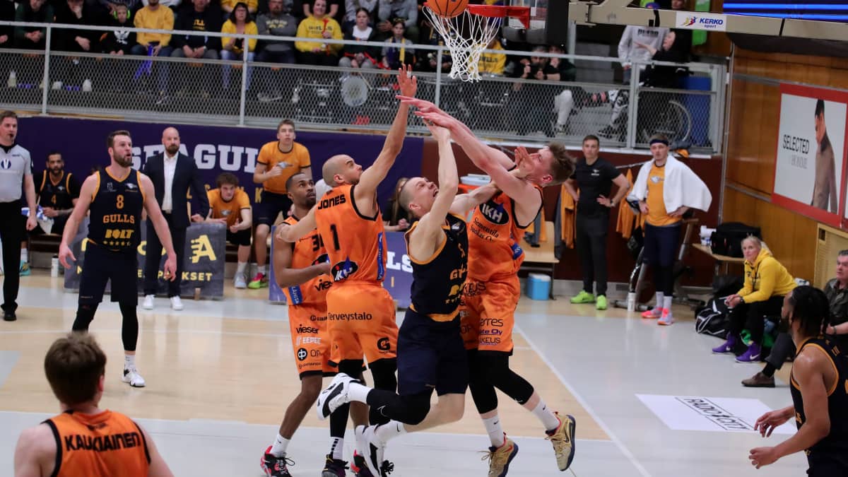 Seagullsin Antti Kanervo heittää korin Karhu Basketin pelaajien yrittäessä turhaan estää sitä.
