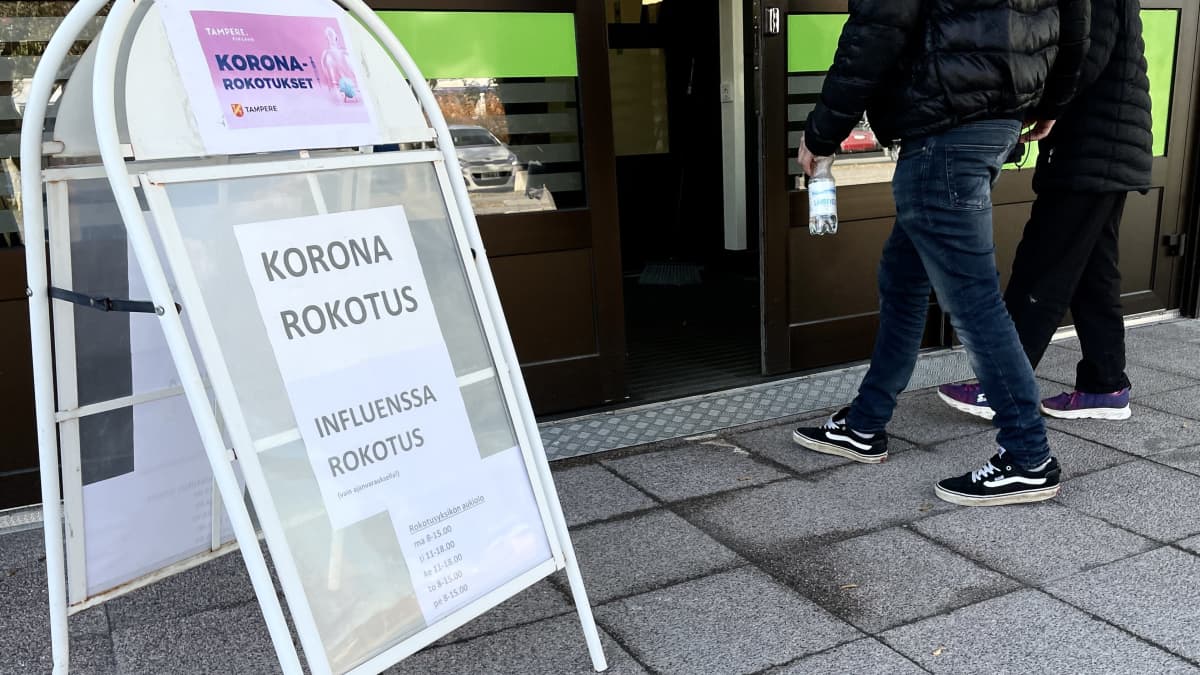 Korona- ja influenssarokotuksista kertova kyltti Hatanpään koronarokotusyksikön ovilla.