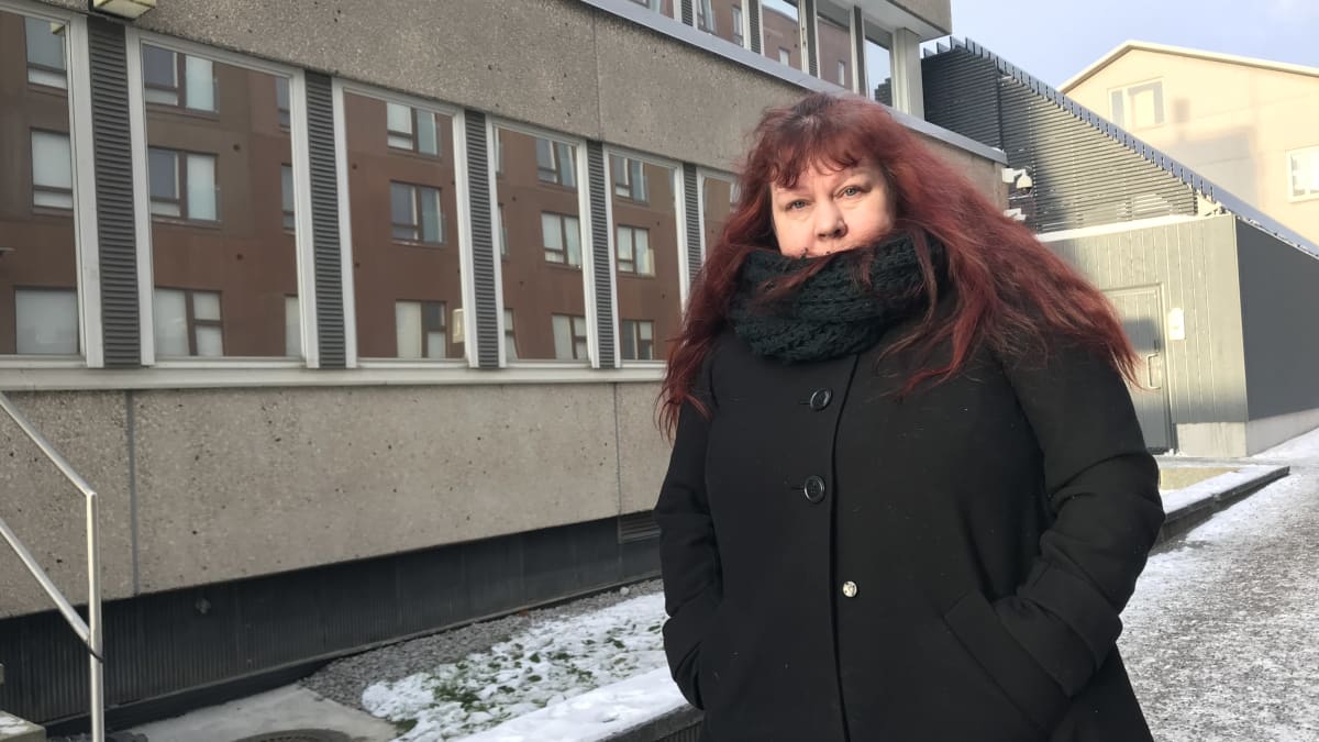 Mari Drah seisoo mustassa talvitakissa Tampereen poliisivankilan ulko-oven edustalla.