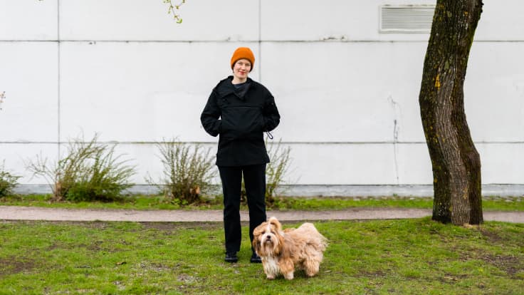 Nanne Pyrhönen ja Nova-koira poseeravat kameralle vaalean rakennuksen edessä.