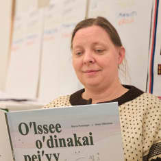 Maria Porsanger lukee kirjoittamaansa koltansaamenkielistä kirjaa. 