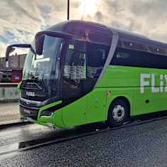 Kuvassa näkyy FlixBusin vihreä bussi Lahden linja-autoasemalla sateisena iltapäivänä. 