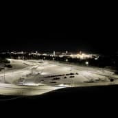 Kirkkaasti valaistu hiihtostadion Ahveniston moottoriradalla. Taustalla näkyy Tiiriön markettialueen valot.