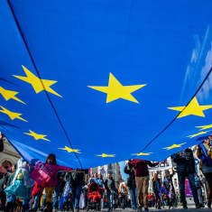 Ihmiset kannattelevat suurta EU:n lippua.
