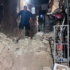A man steps over piles of stone rubble in a lane in Marrakesh after the earthquake. 