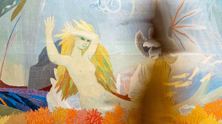 Nainen kävelee Tarina merenpohjasta teoksen edestä.