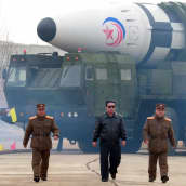 Kim Jong-un kävelee sotilaiden kanssa, taustalla suuri ohjus.