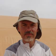 Jukka Viljanen seisoo aavikolla ja katsoo kameraan.