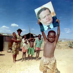 Poika pitää Martti Ahtisaaren kuvaa päänsä päällä Namibian maaseudulla