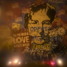 John Lennonin naama maalattuna seinään. Kasvojen ympärillä ja päällä on paljon tekstiä. Alle on asetettu kynttilöitä.