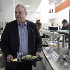 Kärkölän pormestari Markku Koskinen kävelee ruokatarjotin kädessä Kärkölän yhtenäiskoulun ruokasalissa.