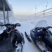 Kaksi moottorikelkkaa lumisessa maisemassa.
