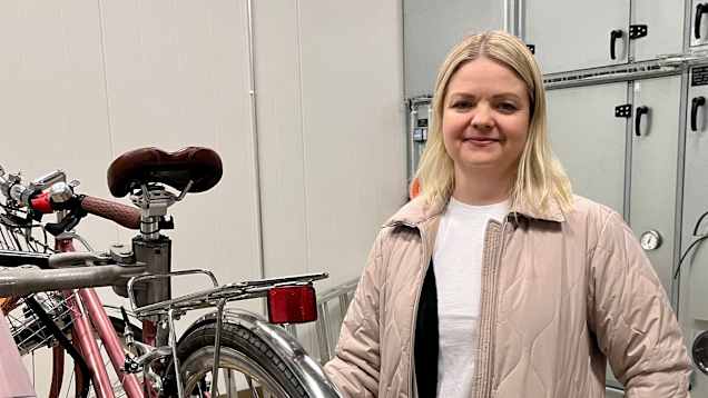 Kvinna står bredvid cykel.