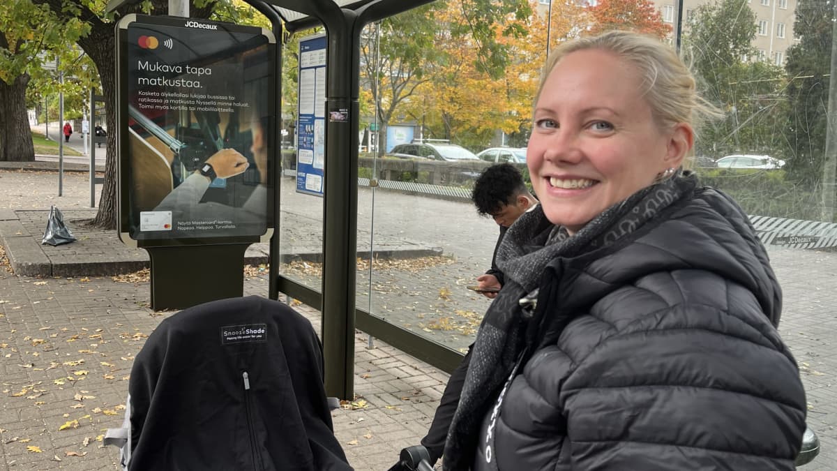 Tamperelainen Anniina Saunajoki odottamassa lastenvaunujen kanssa bussia pysäkillä.