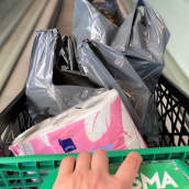 Käsi työntää Prisman ostoskärryjä. Kärryissä muovikasseja ja vessapaperipakkaus. 