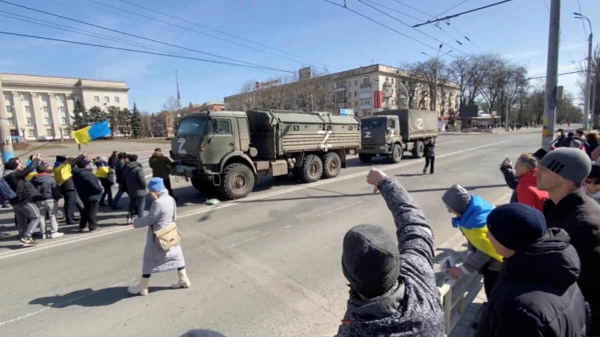Ukrainalaiset mielenosoittajat huutavat venäläisille joukoille autoissa.
