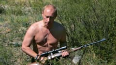 Vladimir Putin ilman paitaa ottaa aurinkoa rannalla.