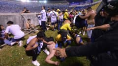 Muut fanit auttavat loukkaantuneita jalkapallostadionilla El Salvadorissa. 