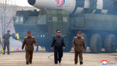 Pohjois-Korean johtaja Kim Jong-un kävelemässä. Taustalla iso ohjus.