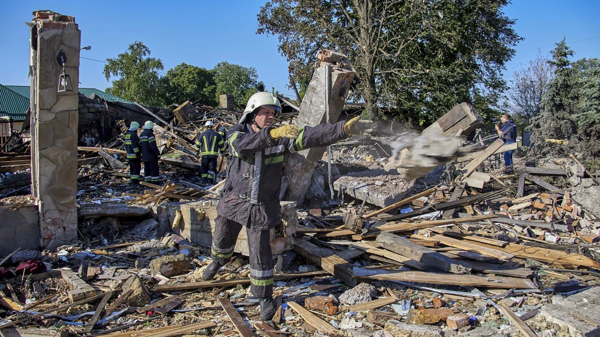 Pelastustyöntekijät siivovat tuhoutuneen rakkennuksen raunioilla.