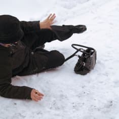 Jalkakäytävällä kaatunut ihminen makaa maassa kyljellään.