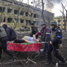 Raskaana olevaa naista kannetaan paareilla pommituksen tuhoaman sairaalan raunioista.