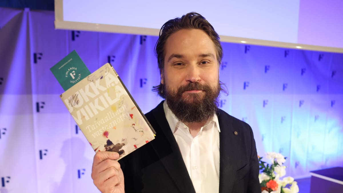 Jukka Viikilä näyttää kirjaansa.