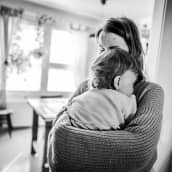 Äiti pitää lasta sylissään. Mustavalkoinen kuva.