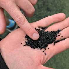 A man's hand holding rubber crumb.