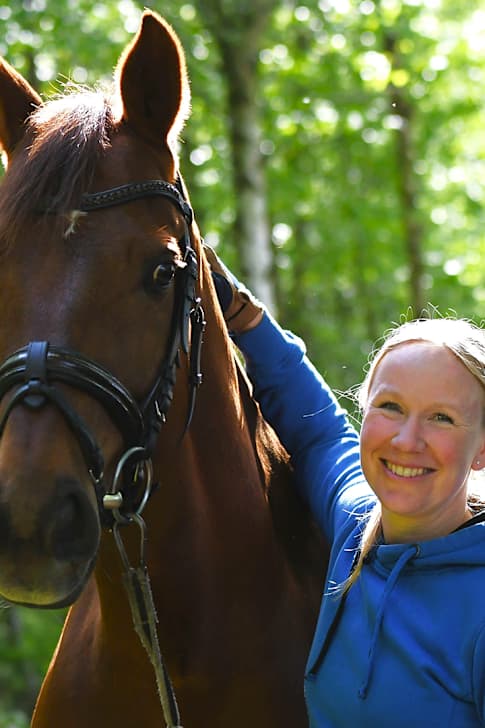 Emma Kanerva hymyilee auringossa hevosensa Greek Air vieressä