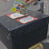 En hand sätter in ett julkort i en svart låda för att senare delas ut till ensamma äldre.