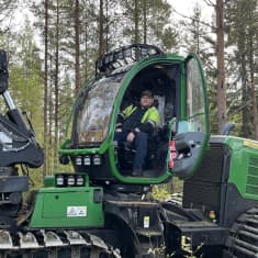 Mies istuu metsäkoneessa ja ovi on auki.