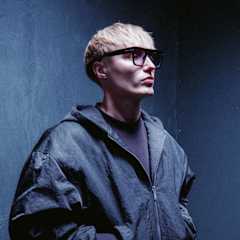 Artisten Isac Elliot iklädd mörka kläder poserar framför en svart vägg.