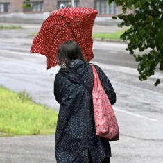 Sateenvarjoa pitelevä jalankulkija.