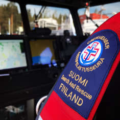 Etualalla Suomen Meripelastusseuran logolla varustetut pelastusliivit, taka-alalla pelastusaluksen navigointilaitteita.