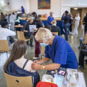 Sairaanhoitaja antaa koronavirusrokotetta oppilaalle.