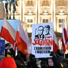 Mielenosoittajia, jotka kantavat Puolan lippuja sekä kylttiä, jossa ilmaistaan tuki Kamińskille ja Wąsikille.