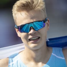 Emil Helander Suomen lippu hartioillaan ja aurinkolasit päässä.