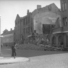 People walking on a bombed-out street.