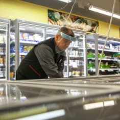Sukevan M-marketin kauppias Jarkko Laukkanen järjestelee pakastettuja ruokatuotteita kaupassaan.