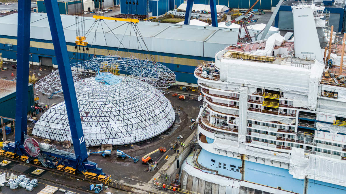 Jättimäinen lasi- ja teräsrakennelma, Dome-nimen saanut kupu Meyer Turun telakalla Icon of the Seas -aluksen vierellä.