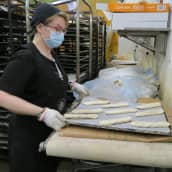 Leipomotyöntekijä Anne Saarela laittaa viinereitä pellille Lapin leipomossa.