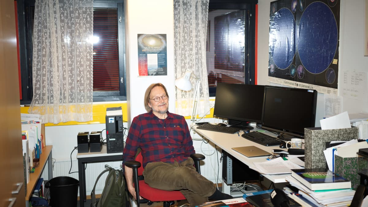 Heikki Salo katselee huoneessa olevaa kirjahyllyä.